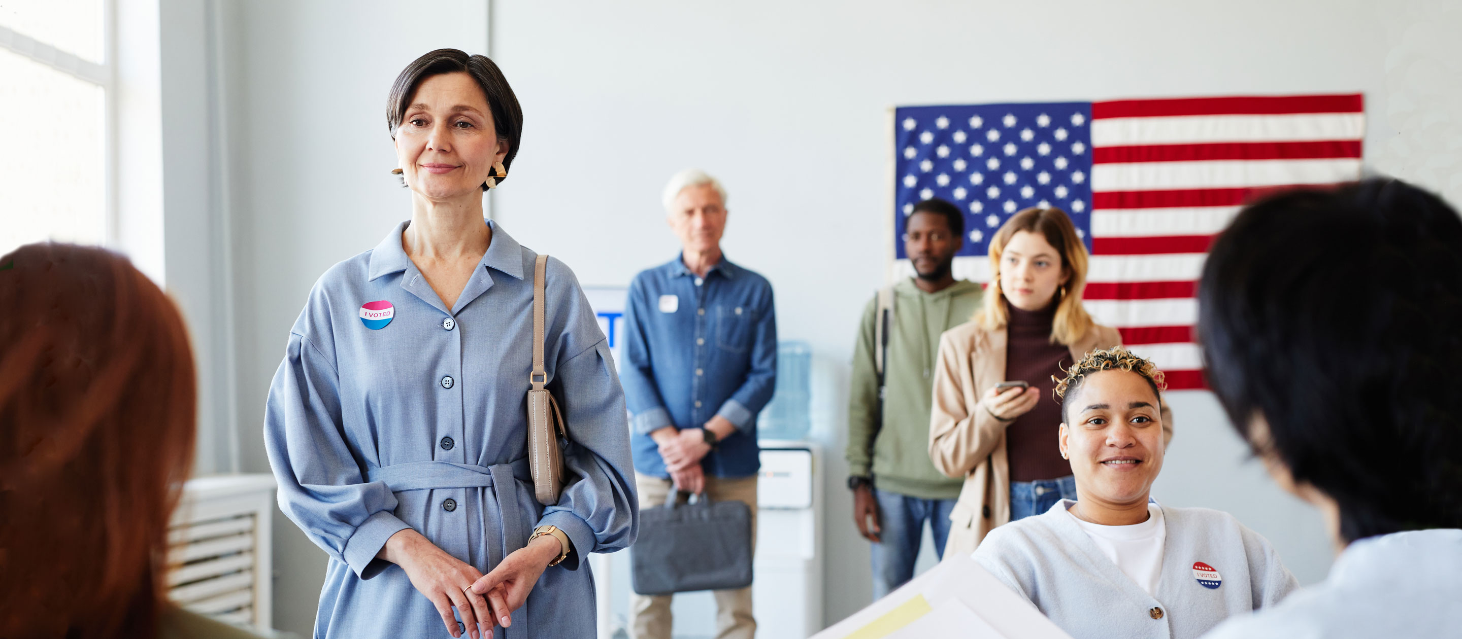 Voters waiting standing in front of an American flag