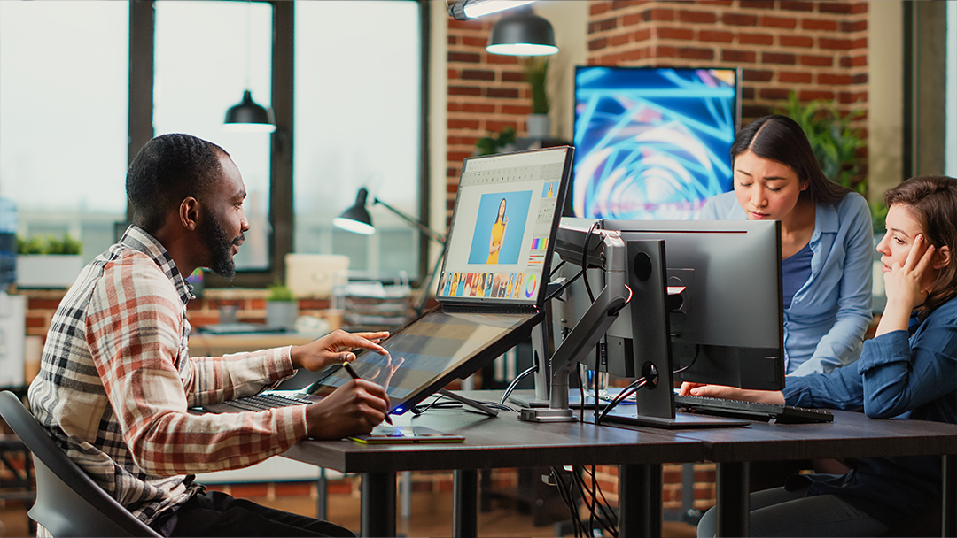 A team of visual designers working on computers in an open office setting